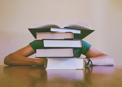 Student sitting behind a large stack of books