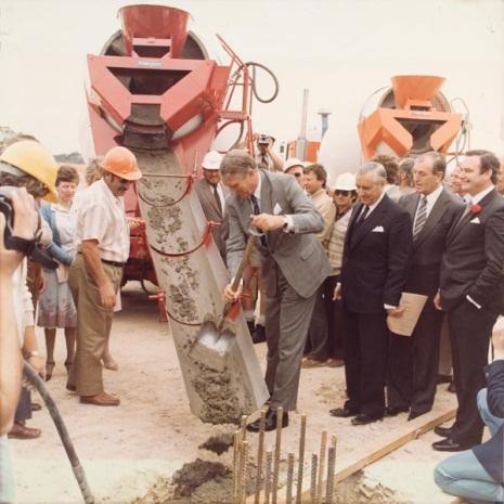 Prime Minister Malcolm Fraser with shovel, pouring concrete at Parliament House construction site, Parliament House Art Collection