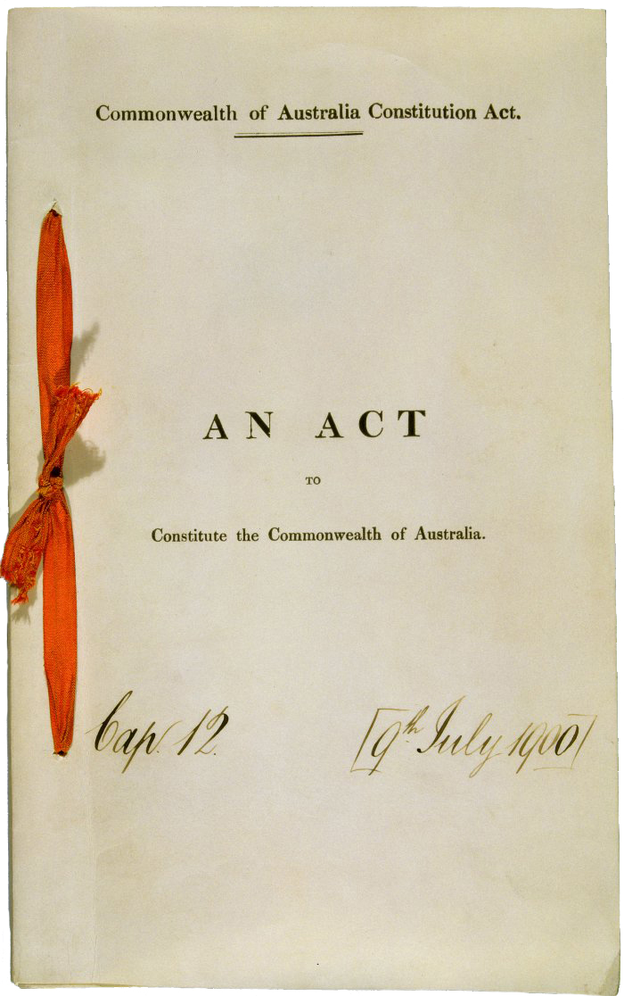 This image shows the front page of the original public record copy of the Commonwealth of Australia Constitution Act 1900. There is a a red ribbon tied in a bow on the left hand side of the document. The paper looks faded from age.