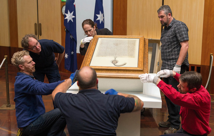 Photograph of staff from Building Fabric Services and Art Collection and Exhibitions installing the 1297 Magna Carta in the Great Hall