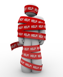 A person is wrapped in red tape marked Help, representing getting caught in a problem or trouble and needing rescue to be freed from the tangled mess 
