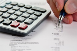 Closeup of calculator, hand, pen and financial statement.