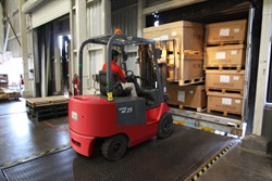 Man operating forklift to unload cargo from a truck